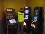 Nielegalne automaty do gier. Funkcjonariusz KAS stoi przy nielegalnych automatach do gier