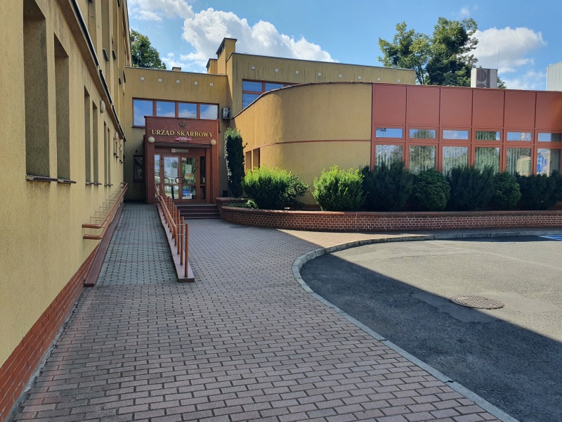 Widok wejścia do budynku urzędu.z przodu podjazd dla osób niepełnosprawnych.Nad wejściem do budynku napis Urząd Skarbowy