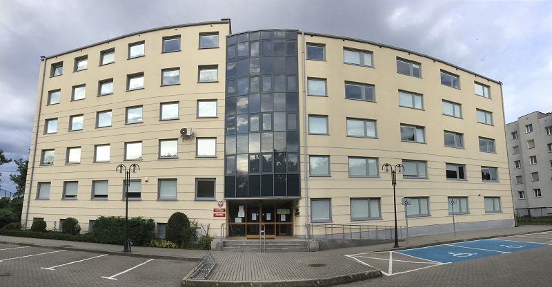 Widok fasady budynkui urzędu od strony głównego wejścia.Przed budynkiem pusty parking.