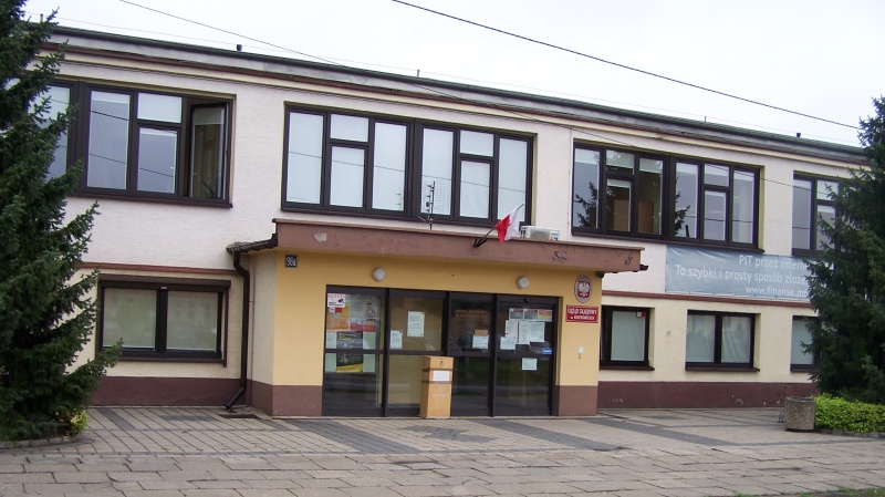 Widok fasady budynku urzędu z oknami. Przed budynkiem chodnik wyłożony kostką.