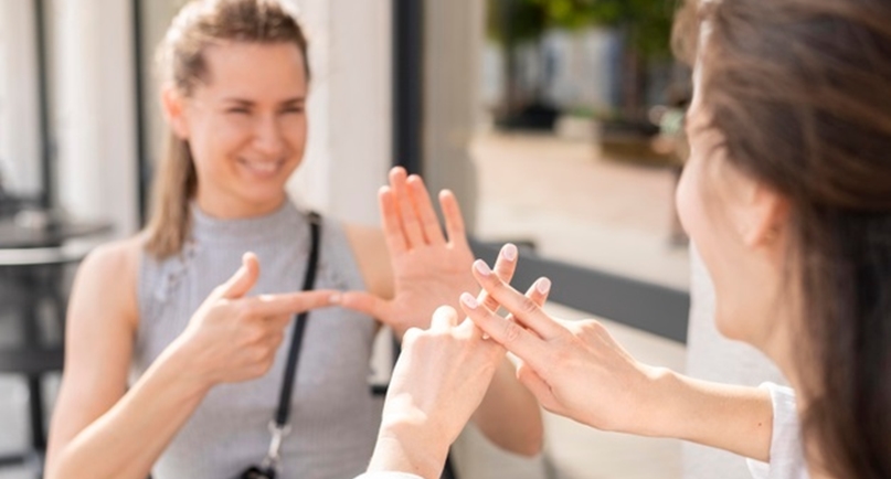 Uśmiechnięte kobiety rozmawiające w języku migowym