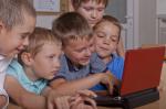 #poDARujkomputer to wspólna akcja GovTech Polska i Ministerstwa Finansów. Na zdjęciu pięciu chłopców, z bliska, ujecie twarzy, prawdopodobnie pierwszoklasistów, którzy patrzą na ekran komputera.