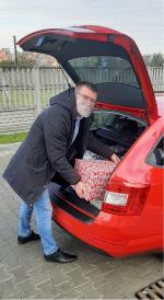 pracownik urzędu skarbowego w Namysłowie wkłada do bagażnika samochodu prezenty