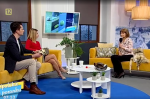 Zdjęcie studio telewizyjne, na kanapie siedzi ekspertka opolskiej KAS w prawej dłoni trzyma mikrofon, z boku na fotelu siedzi prezenterka telewizyjna i prezenter telewizyjny