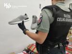 funkcjonariusz Służby Celno-Skarbowej trzyma w but sportowy z podrobionym znakiem towarowym