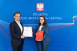 Szef KAS Magdalena Rzeczkowska i  prezes firmy SIG na tle baneru Krajowej Administracji Skarbowej