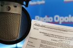 mikrofon radiowy, w tle druk zeznania podatkowego, w oddali napis Radio Opole