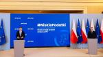 Premier Mateusz Morawiecki i Minister Artur Soboń na konferencji prasowej. Każdy z nich stoi przed mównicą z mikrofonem, za nimi ekran z napisem Niskie Podatki Rząd przyjął projekt zmian, po prawej stronie flagi Polski i Unii Europejskiej