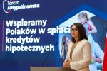 konferencja prasowa, Minister Finansów stoi przed mównicą, za nią ekran z napisem Tarcza Antyputinowska Wspieramy Polaków w spłacie kredytów hipotecznych