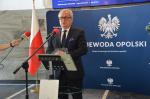 Wojewoda Opolski stoi przy mównicy. W tle baner Urżędu Wojewódzkiego w Opolu
