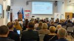 Sala konferencyjna. Uczestnicy konferencji siedzą i słuchają dyskusji. Przed nimi uczestnicy panelu dyskusyjnego.