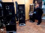 2 otwarte automaty do gier, w tle funkcjonariusz tnie piłą do cięcia metali automat do gier hazardowych