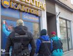 dwóch funkcjonariuszy Służby Celno-Skarbowej i jeden funkcjonariusz Straży Granicznej stoją przodem do budynku w którym znajduje się kantor
