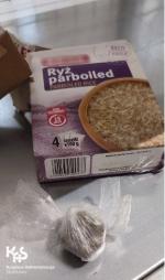 pudełko i torebka ryżu, obok zawiniątko z narkotykami