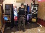 w pomieszczeniu funkcjonariusz KAS stoi tyłem do trzech nielegalnych automatów do gier hazardowych