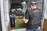 funkcjonariusz Służby Celno-Skarbowej stoi przed samochodem dostawczym wypełnionym butelkami z nielegalnym alkoholem
