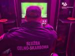 Zdjęcie przedstawiające funkcjonariusza Służby Celno-Skarbowej, który siedzi przed automatem do gier