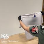Funkcjonariuszka Służby Celno-Skarbowej prezentuje egzemplarz podrobionego ubrania