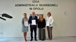 Dyrektor Izby Administracji Skarbowej w Opolu stoi razem z wyróżnionymi osobami; dwie kobiety i jeden mężczyzna trzymają w dłoniach dyplomy