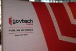 Logo GovTech umieszczone na stojącym banerze. Czarny napis „govtech