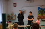 Funkcjonariusze opolskiej KAS na spotkaniu w sali lekcyjnej, obok funkcjonariuszy stoi dziewczynka z przedszkola z różowej koszulce