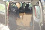 Funkcjonariuszka KAS stoi przy otwartym bagażniku samochodu w którym znajdują się przezroczyste butelki z alkoholem oraz kartony z butelkami